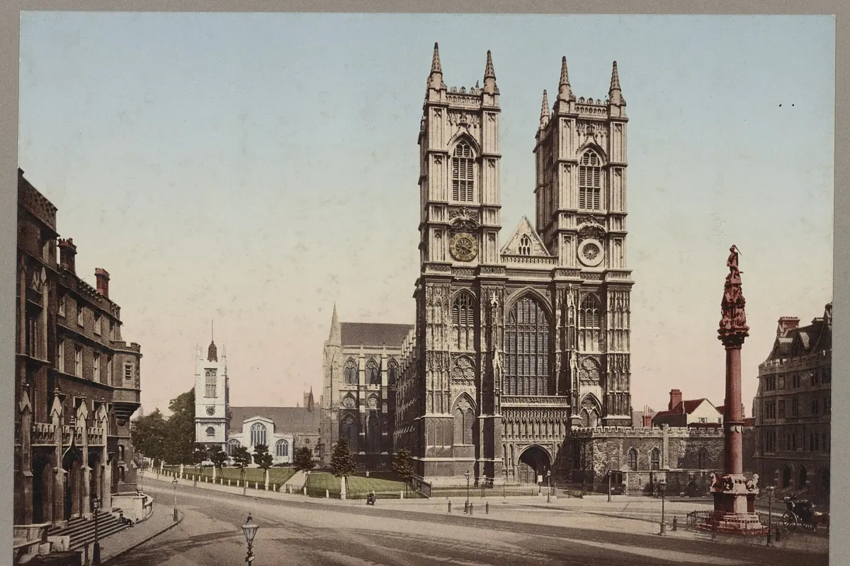 Et gammelt farvefotografi af Westminster Abbeys vestfacade, med to stentårne, der rejser sig bag en gade og en høj søjle.
