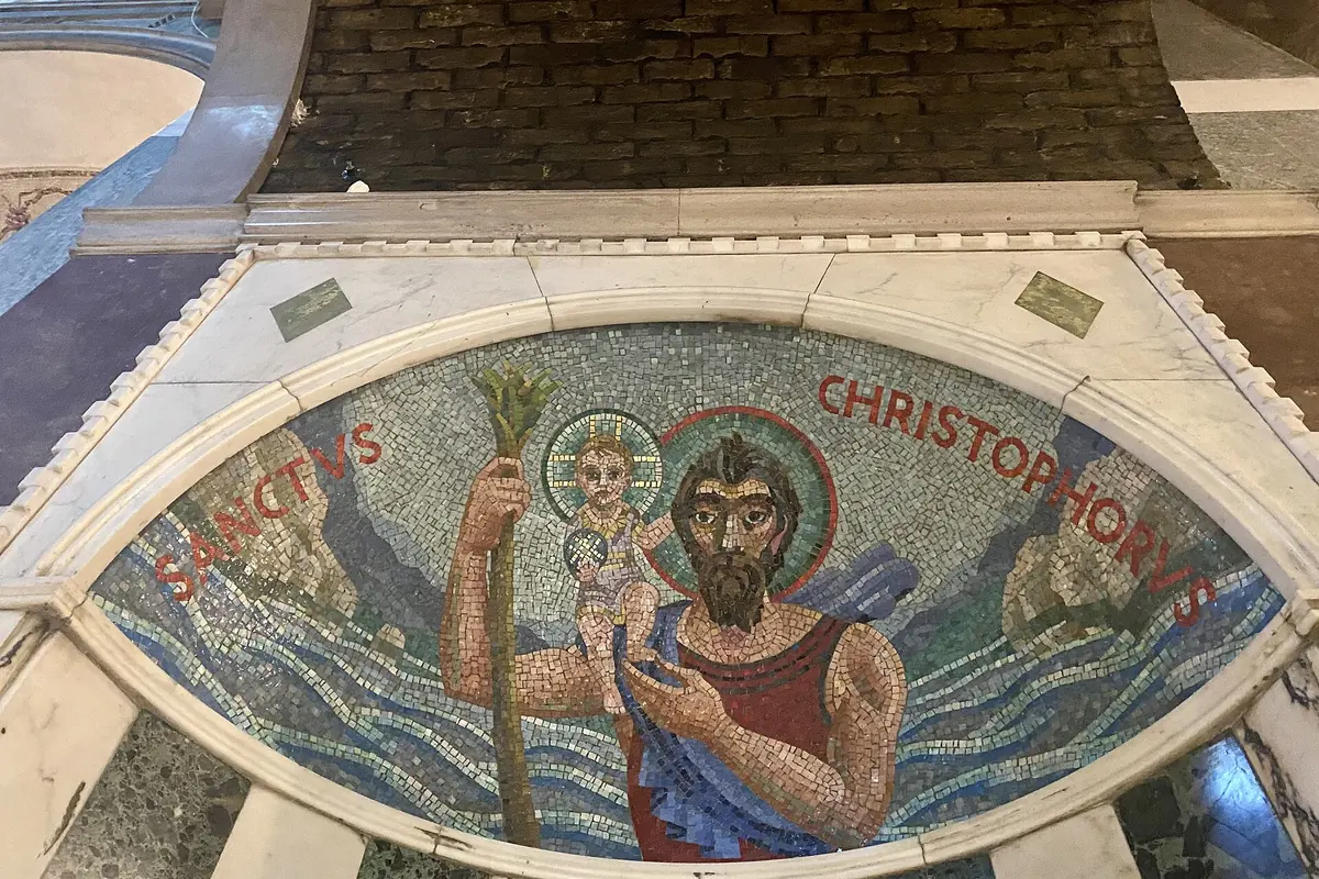 Un mosaico de San Cristóbal en un marco de mármol bajo una bóveda de ladrillo visto en una capilla lateral.