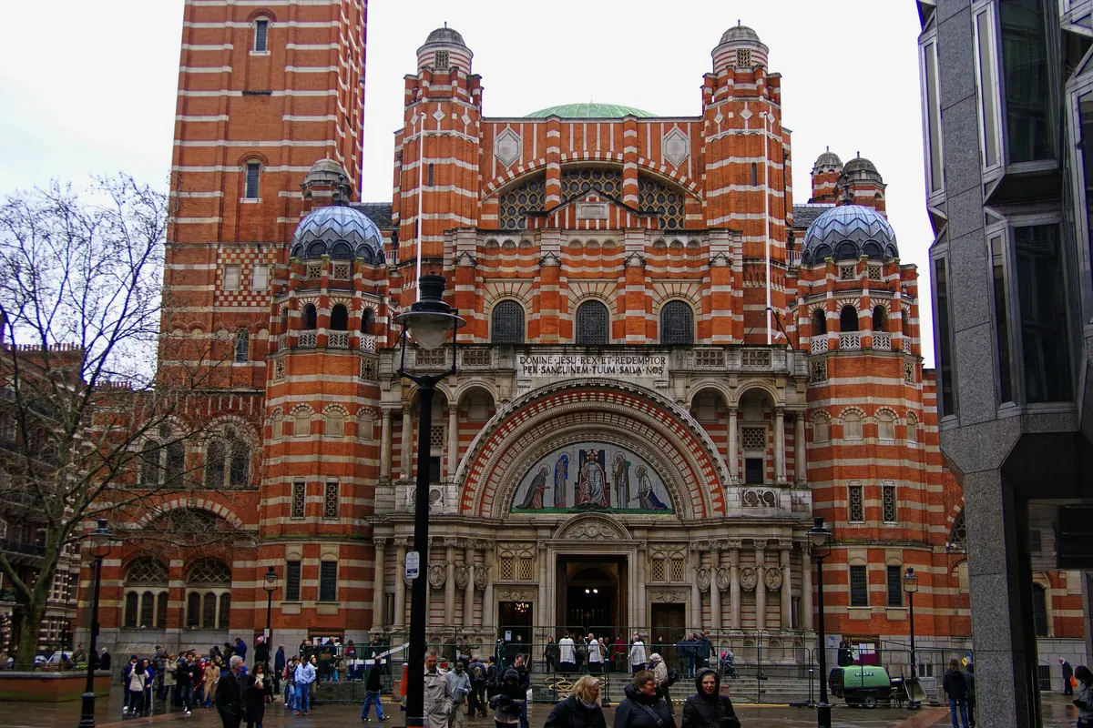 La fachada oeste de la Catedral de Westminster desde Victoria Street, de ladrillo rojo combinado con piedra, con torrecillas con cúpula y el campanario.